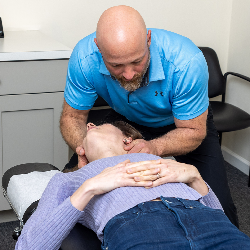 Dr Eric Chludzinski giving her a neck pain treatment